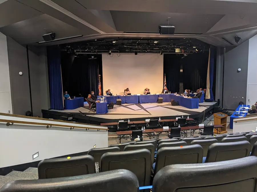 A school board meets on a high school auditorium stage