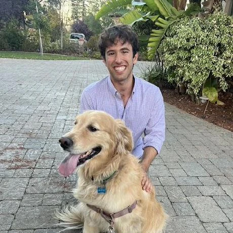 Ben Guzovsky crouching beside his golden retriever